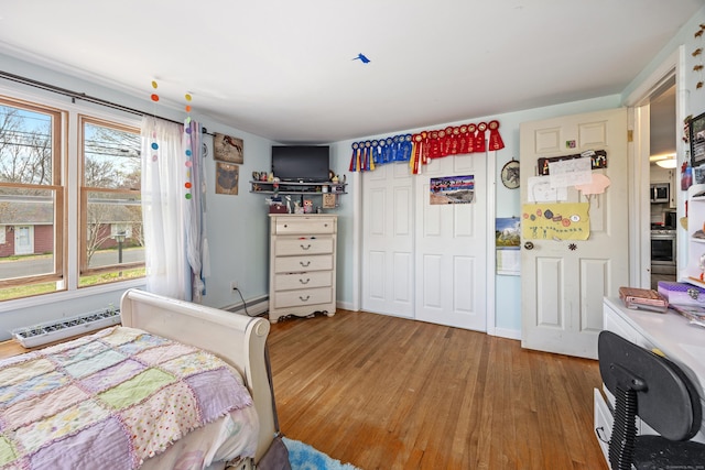 bedroom featuring a closet, baseboard heating, and wood finished floors