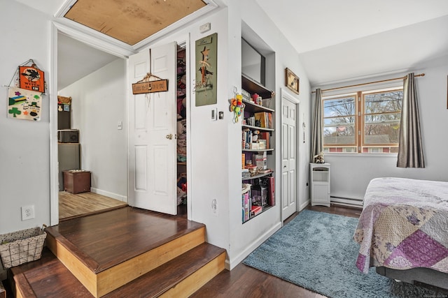 bedroom featuring a baseboard heating unit, vaulted ceiling, wood finished floors, and baseboards