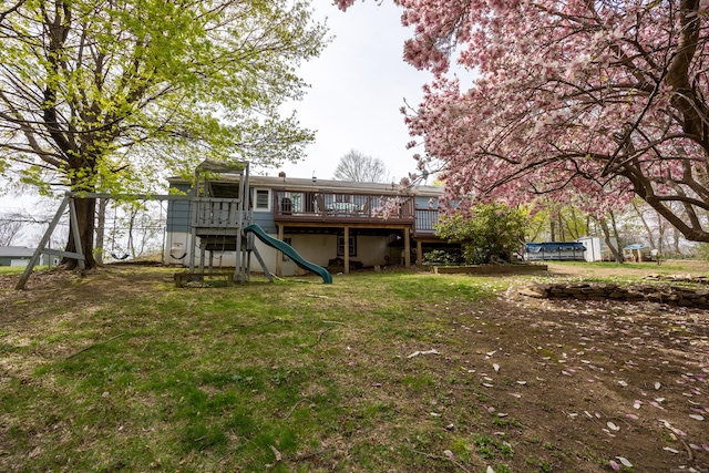 back of property featuring a deck, a yard, and a playground