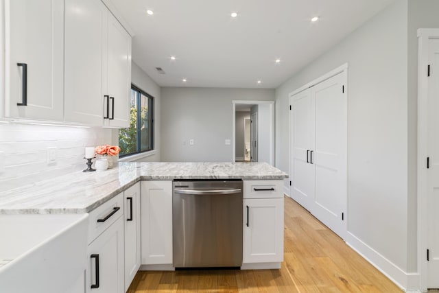 kitchen featuring white cabinets, dishwasher, light wood-style floors, decorative backsplash, and a peninsula
