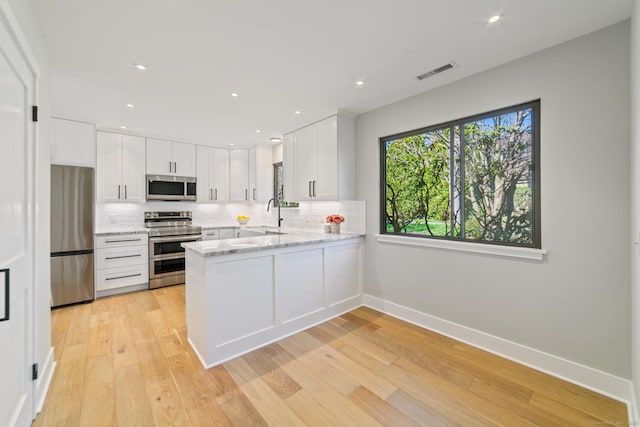 kitchen featuring white cabinetry, visible vents, decorative backsplash, and stainless steel appliances
