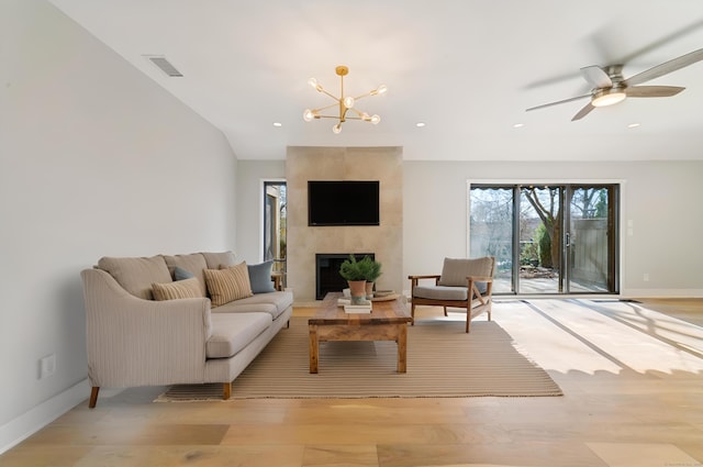 living area with a tile fireplace, visible vents, baseboards, and light wood-type flooring