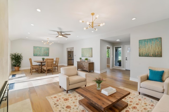 living area with recessed lighting, light wood-style flooring, baseboards, and ceiling fan with notable chandelier