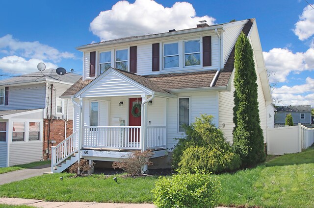 view of front of home featuring fence, a chimney, a porch, and a front lawn