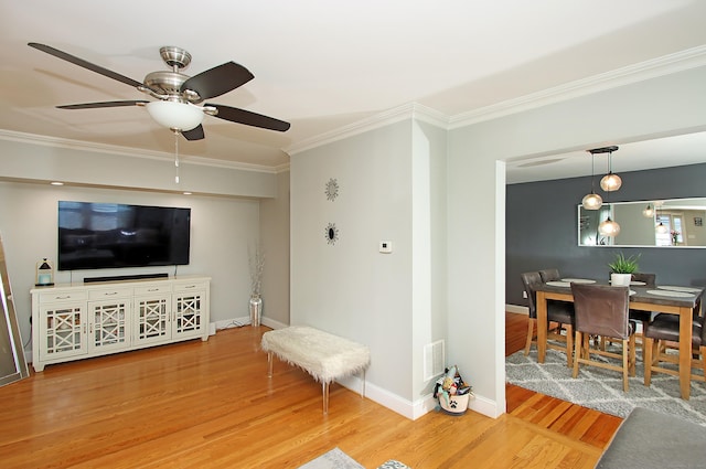 living room featuring ceiling fan, visible vents, crown molding, wood finished floors, and baseboards