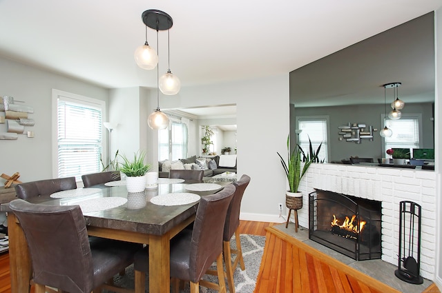 dining room featuring baseboards, wood finished floors, a wealth of natural light, and a fireplace