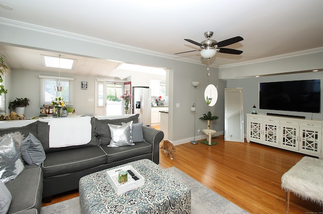 living area featuring crown molding, baseboards, a ceiling fan, and wood finished floors