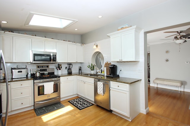 kitchen featuring decorative backsplash, white cabinetry, a sink, light wood-style flooring, and stainless steel appliances