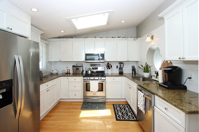 kitchen featuring white cabinetry, appliances with stainless steel finishes, decorative backsplash, and a sink