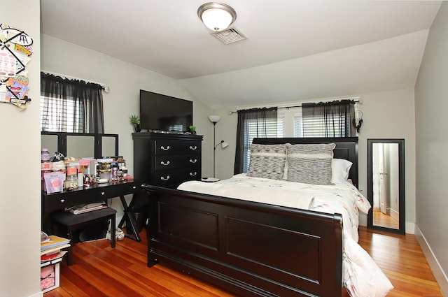 bedroom with visible vents, baseboards, vaulted ceiling, and light wood-type flooring