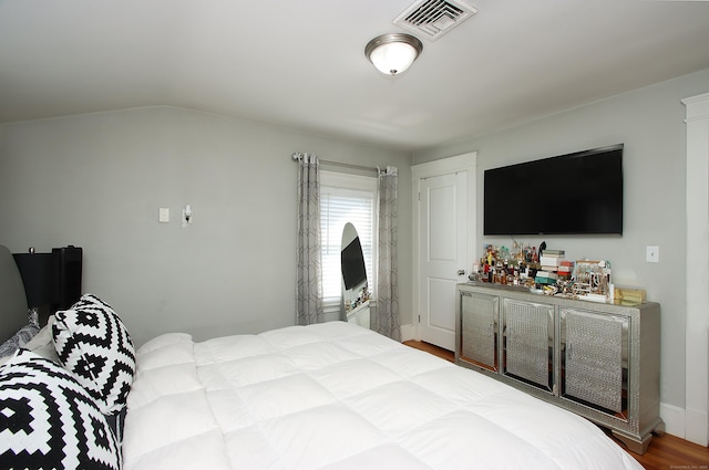 bedroom with baseboards, visible vents, and wood finished floors
