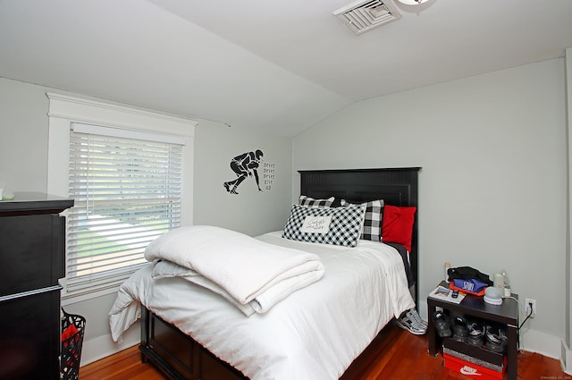 bedroom with visible vents, wood finished floors, and vaulted ceiling