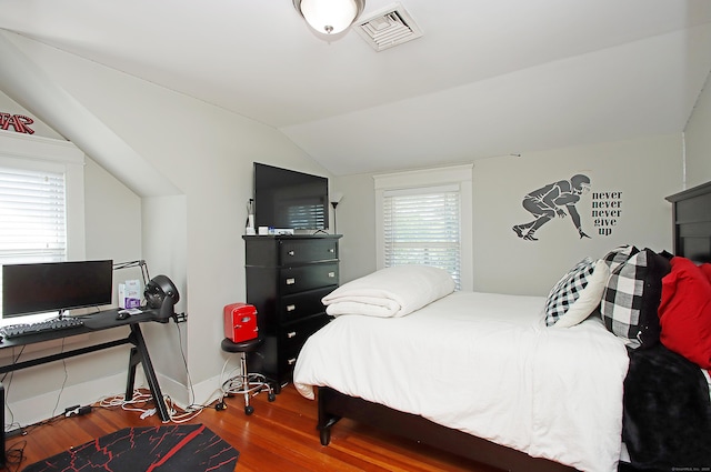 bedroom with baseboards, lofted ceiling, wood finished floors, and visible vents