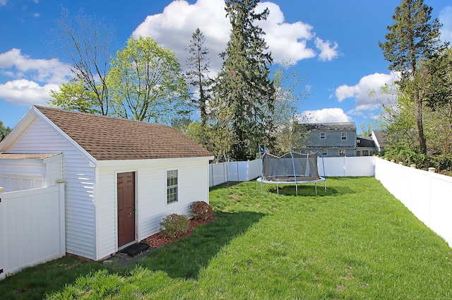 view of yard featuring an outdoor structure, a fenced backyard, and a trampoline