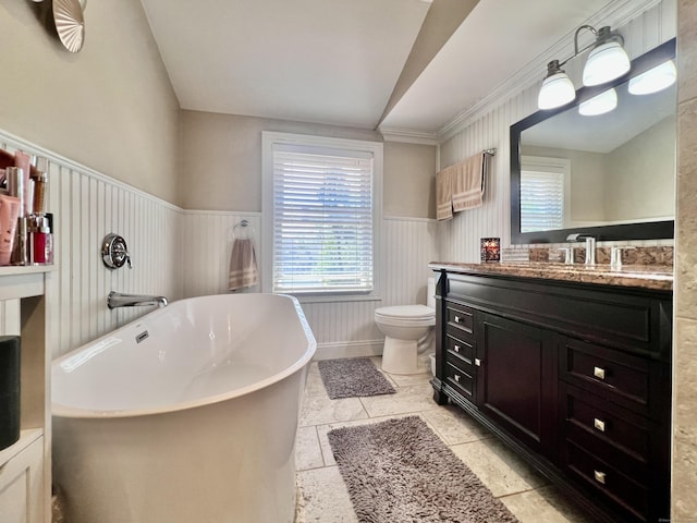full bathroom featuring wainscoting, vanity, toilet, lofted ceiling, and a soaking tub