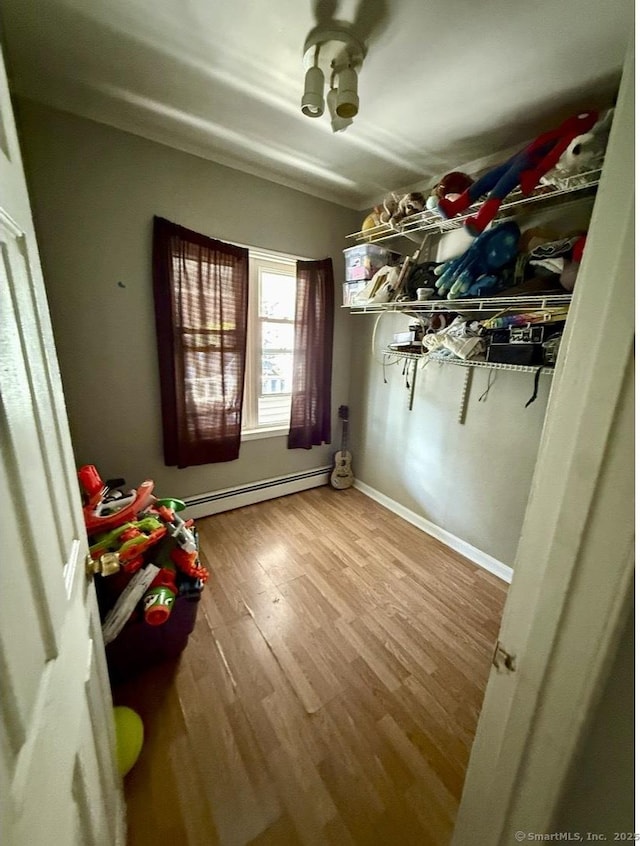 interior space with baseboards, a baseboard heating unit, and wood finished floors