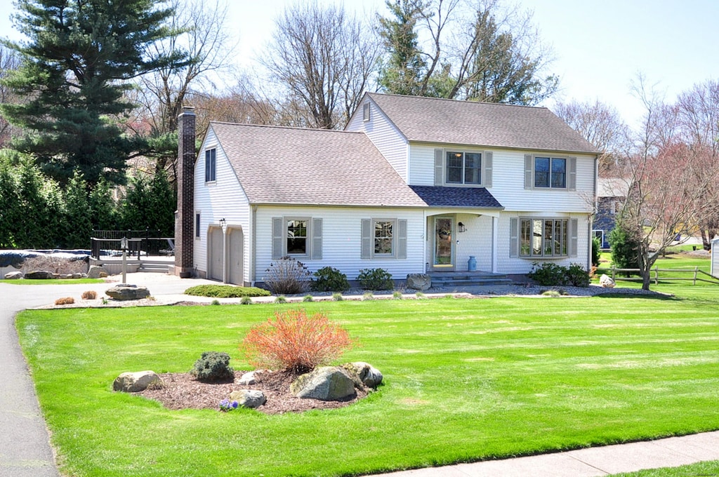 24 Carriage Dr, South Windsor, CT 06074 - view of front facade featuring a chimney, a front lawn, driveway, fence, and a garage