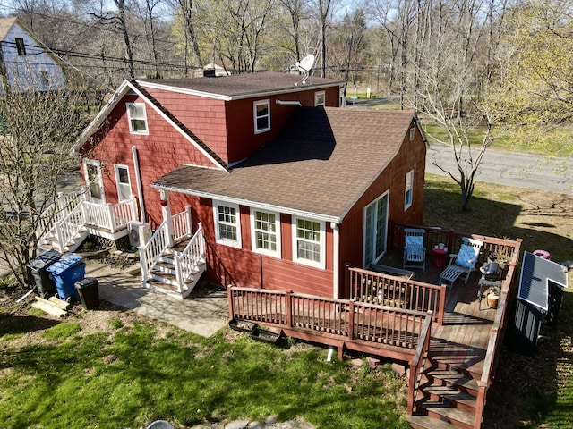 back of property with a chimney, a wooden deck, roof with shingles, and stairway