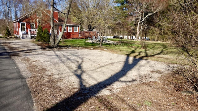 exterior space with a wooden deck, a chimney, and aphalt driveway