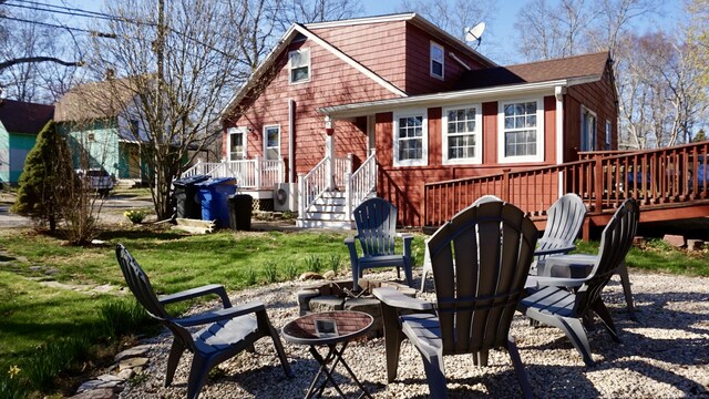 back of house with a wooden deck, a yard, and an outdoor fire pit