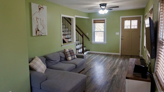 living room featuring baseboards, a ceiling fan, wood finished floors, and stairway