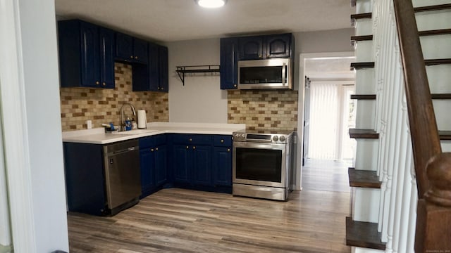 kitchen with blue cabinetry, appliances with stainless steel finishes, tasteful backsplash, and a sink