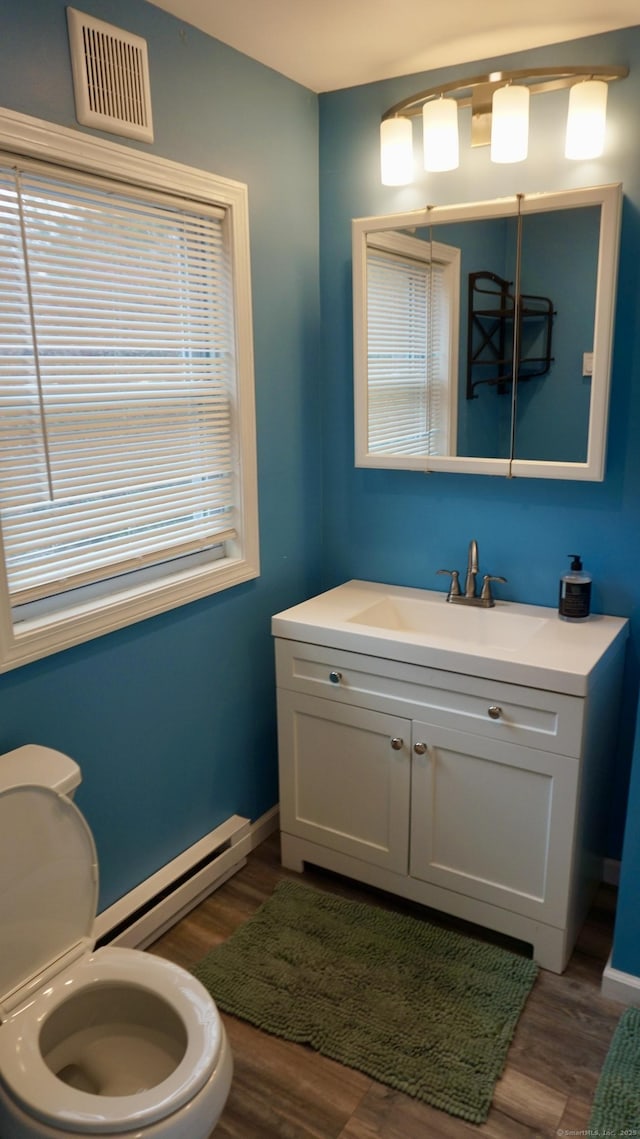 bathroom with wood finished floors, visible vents, toilet, and baseboard heating