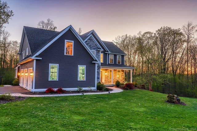 view of front of home featuring driveway, a yard, covered porch, and a garage
