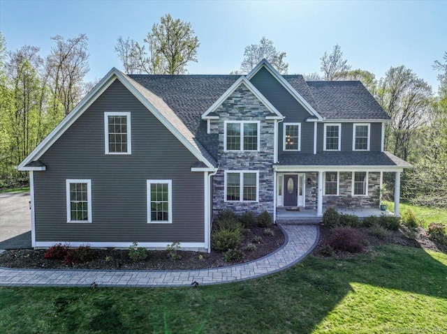 view of front of property with a front lawn, stone siding, and covered porch