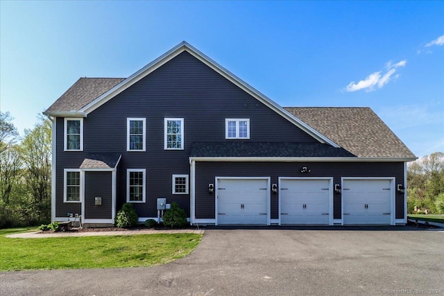 view of front of property featuring driveway, a shingled roof, and a garage