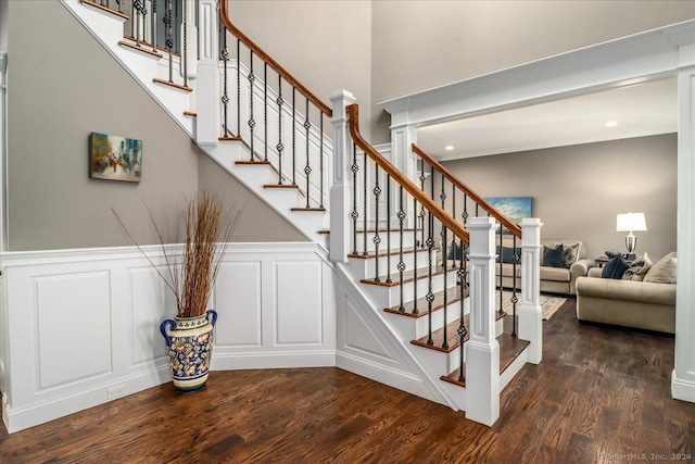 stairway with wood finished floors, a decorative wall, and wainscoting