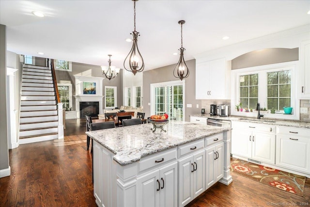 kitchen featuring tasteful backsplash, a center island, dark wood-style flooring, and a sink