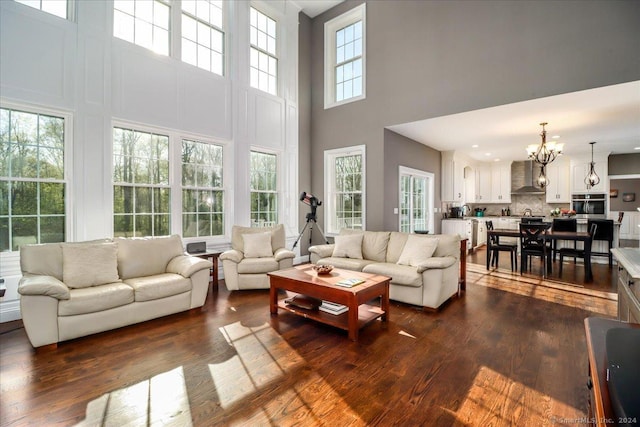 living room with dark wood-style flooring, a chandelier, and a towering ceiling