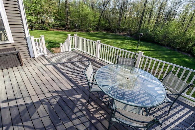 deck featuring outdoor dining space and a lawn