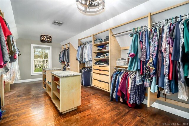 walk in closet with lofted ceiling, visible vents, and dark wood-style floors