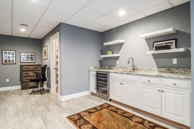 bar with wine cooler, visible vents, a sink, baseboards, and light wood-style flooring