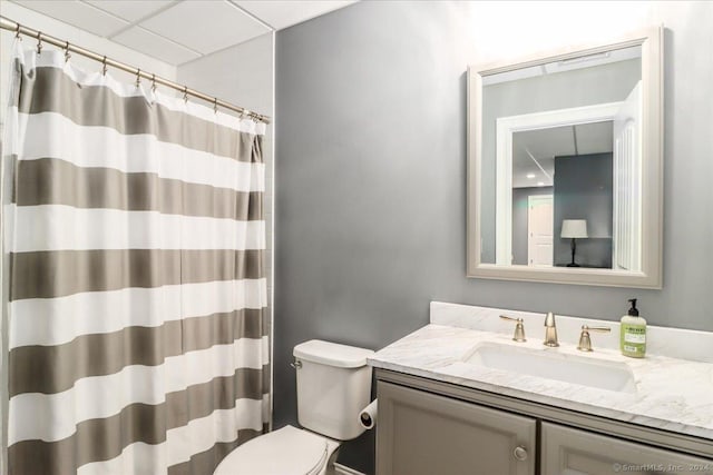 bathroom with a shower with curtain, a paneled ceiling, vanity, and toilet