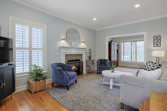 living room featuring crown molding, light wood-type flooring, a fireplace, and recessed lighting