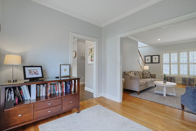 sitting room with stairway, ornamental molding, baseboards, and wood finished floors
