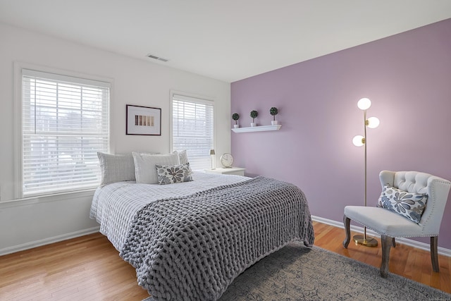 bedroom with baseboards, light wood-style flooring, and visible vents