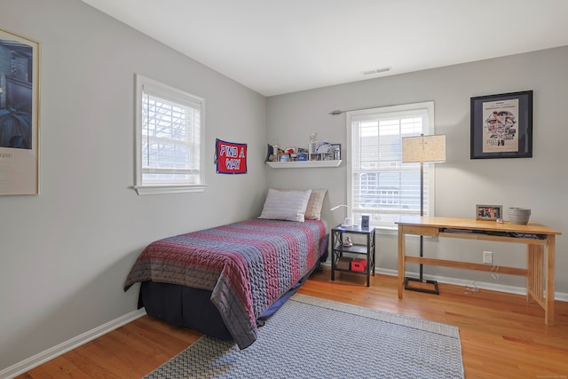 bedroom with visible vents, wood finished floors, and baseboards