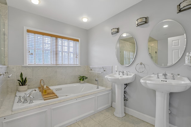 bathroom featuring baseboards, tile patterned flooring, a sink, and a bath
