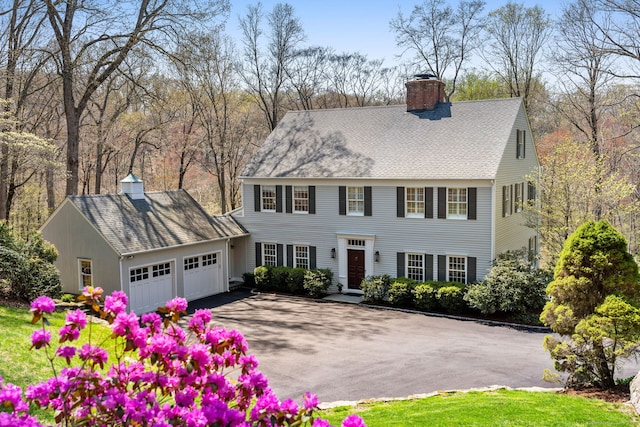 6 Wahackme Ln, New Canaan, CT 06840 - view of front of house with an attached garage, driveway, a chimney, and roof with shingles