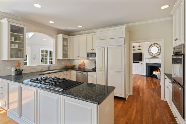 6 Wahackme Ln, New Canaan, CT 06840 - kitchen featuring appliances with stainless steel finishes, a sink, a fireplace with flush hearth, wood finished floors, and glass insert cabinets