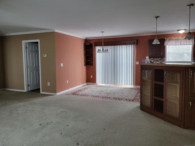 unfurnished living room with crown molding, carpet flooring, baseboards, and an inviting chandelier