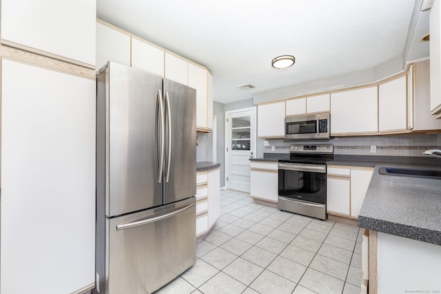 31 Mountain View Dr, Rocky Hill, CT 06067 - kitchen featuring stainless steel appliances, dark countertops, light tile patterned floors, decorative backsplash, and cream cabinets