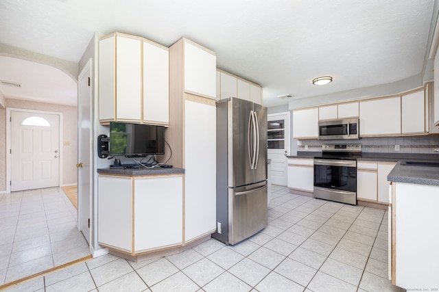 31 Mountain View Dr, Rocky Hill, CT 06067 - kitchen featuring appliances with stainless steel finishes, light tile patterned floors, backsplash, dark countertops, and arched walkways