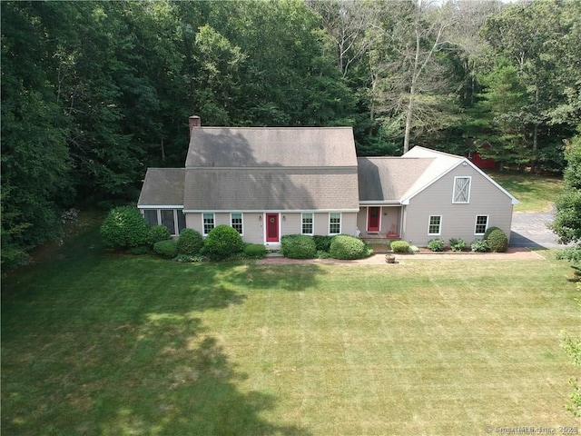 cape cod home featuring a chimney and a front yard