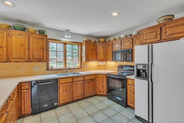 kitchen featuring black appliances, brown cabinets, a sink, and light countertops