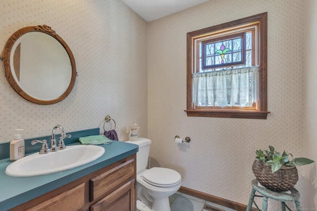 bathroom with wallpapered walls, toilet, and vanity
